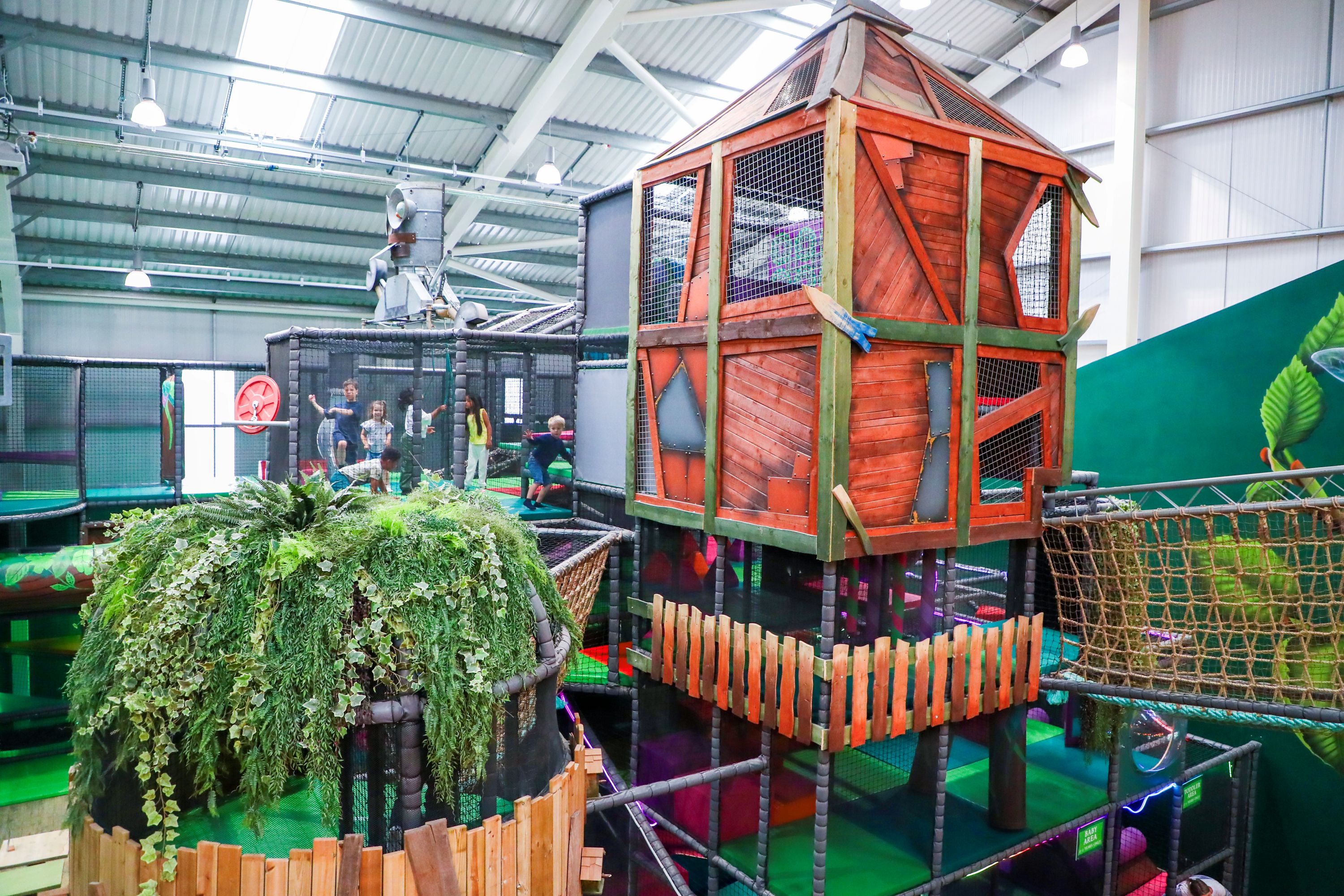 Children climbing multi-level soft play frames at indoor play area in Hounslow