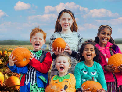 Children holding pumpkins in a pumpkin field