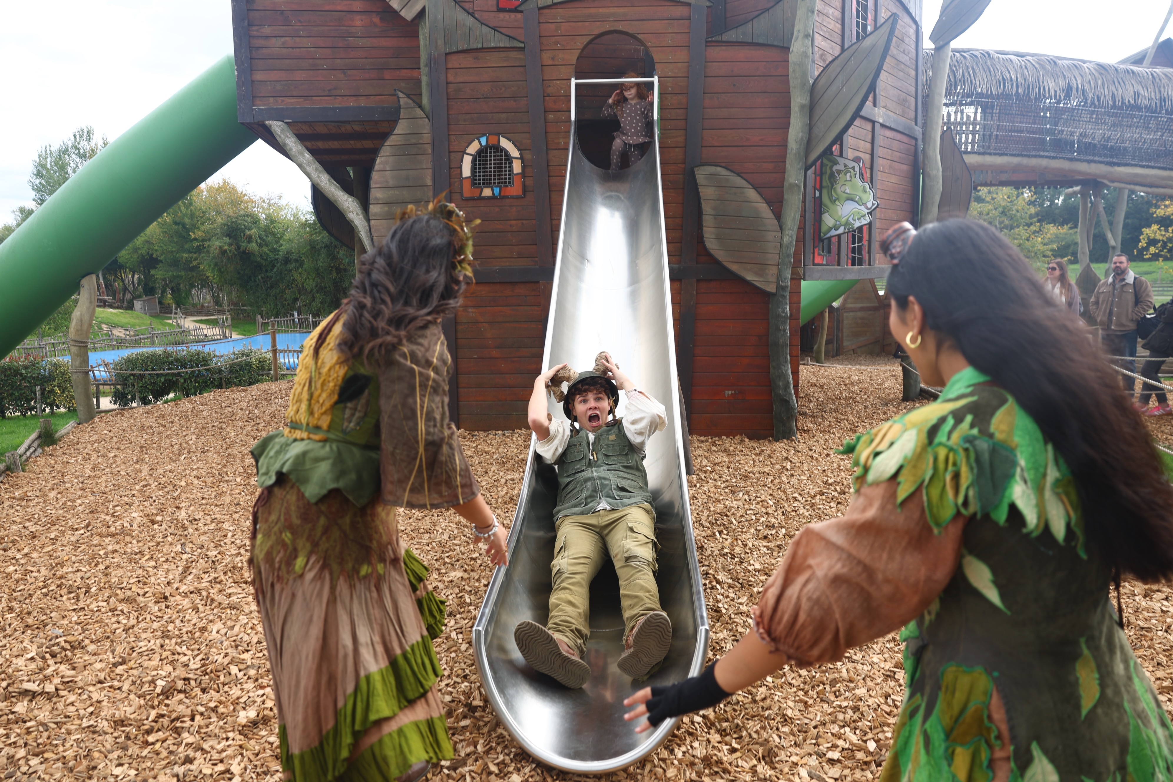 Hobbledown characters interacting with a child sliding down a tower slide in the adventure playground