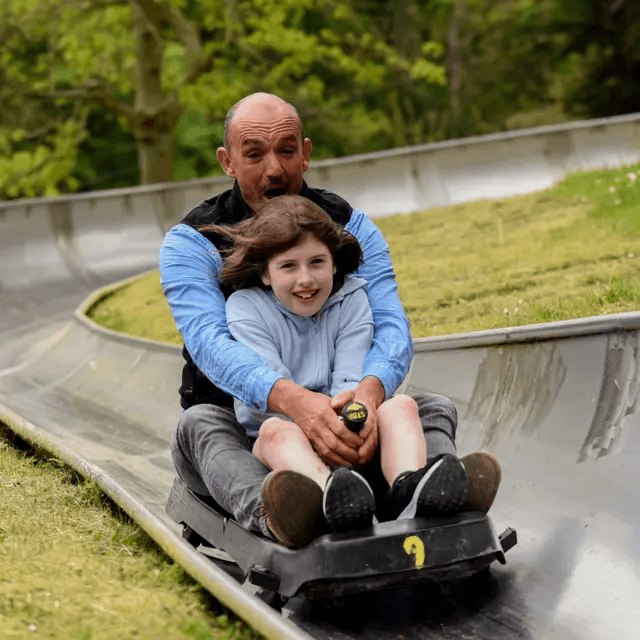 Nick de Canole, founder of Hobbledown, enjoying a toboggan ride with a child