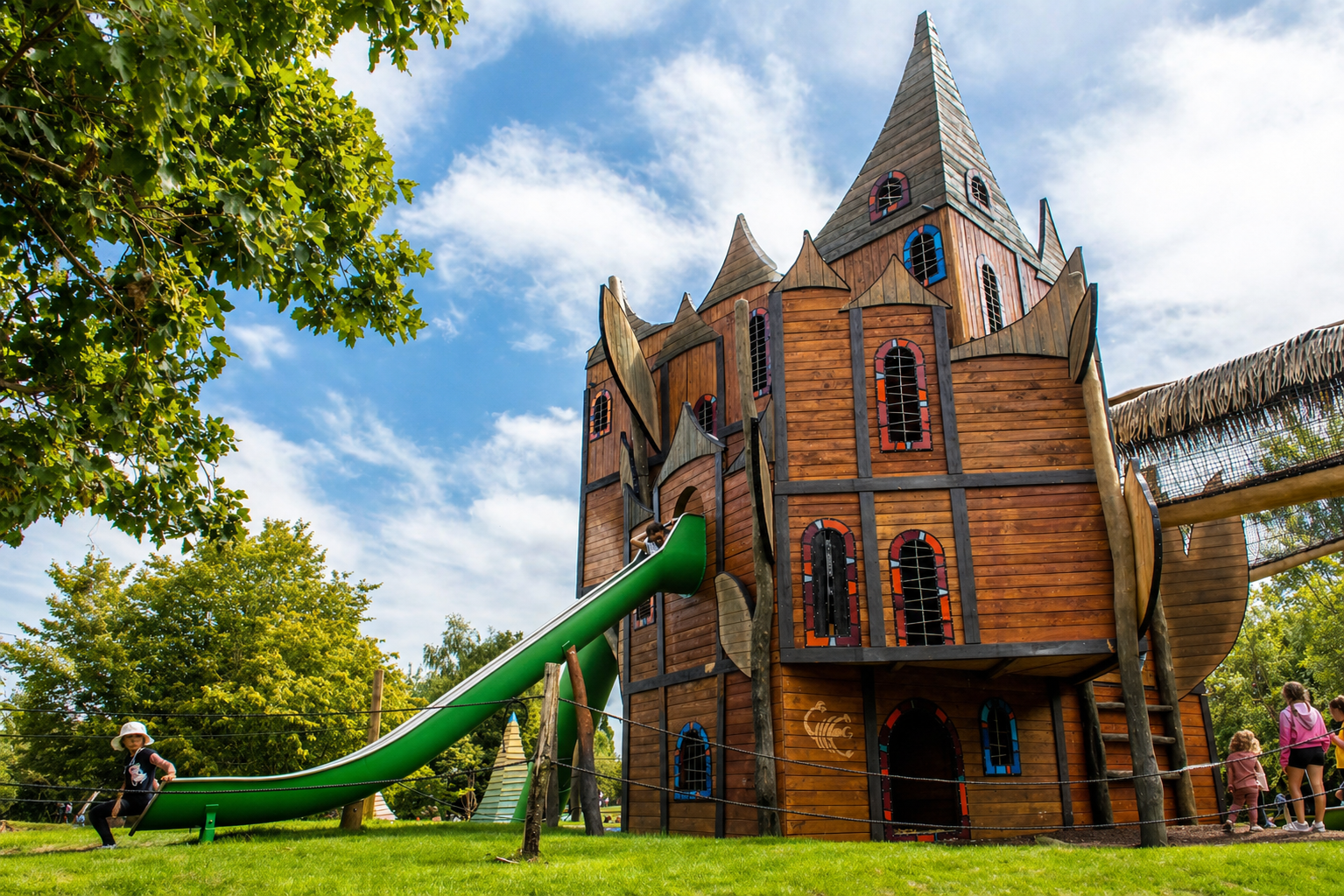 Children playing on a wooden castle playground with slide at Hobbledown Epsom adventure park