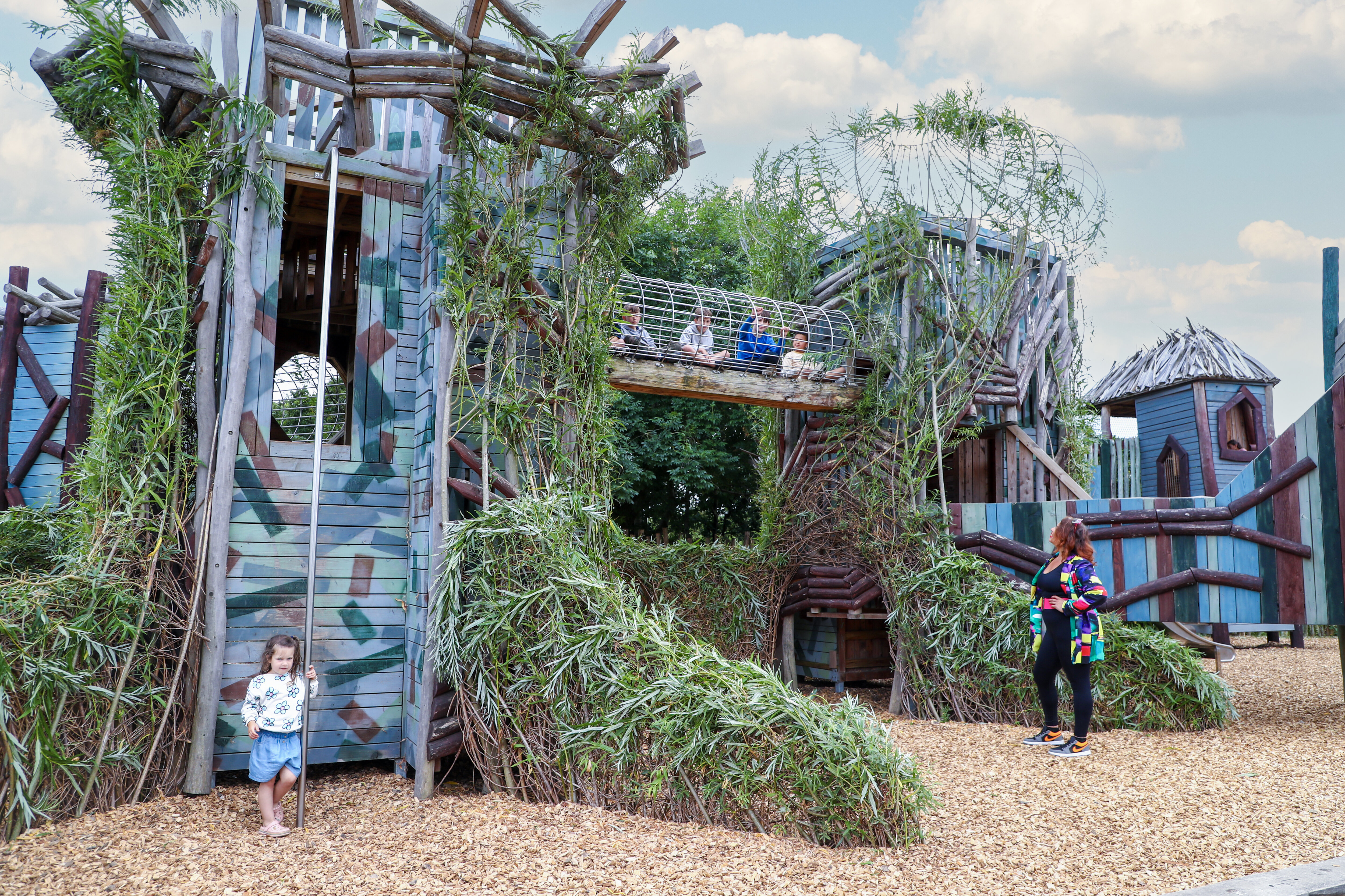 Ivy-covered fantasy castle adventure play structure with children and families exploring at Hobbledown Heath, Hounslow, West London