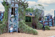 Ivy-covered fantasy castle adventure play structure with children and families exploring at Hobbledown Heath, Hounslow, West London