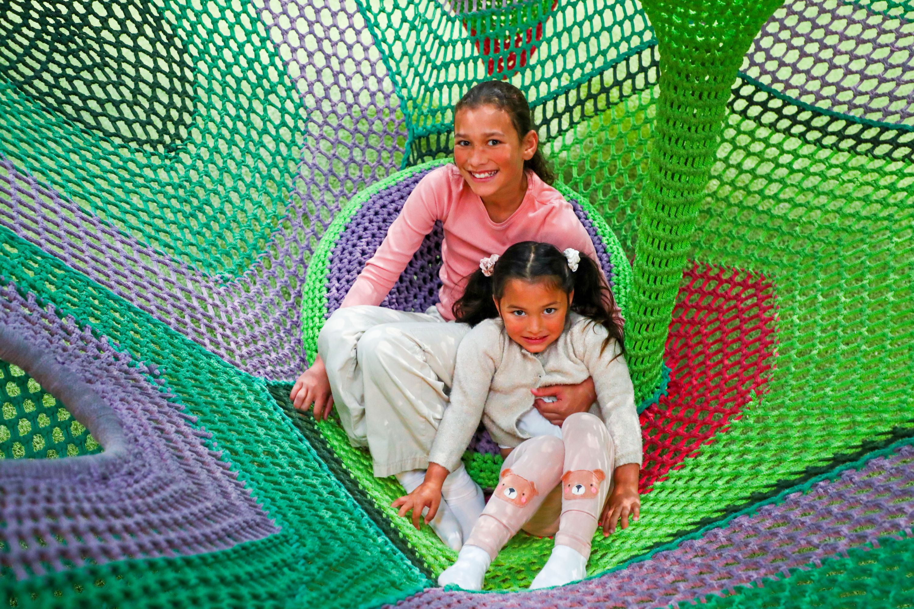 Children playing in crochet hammock play area at indoor play area in Hounslow