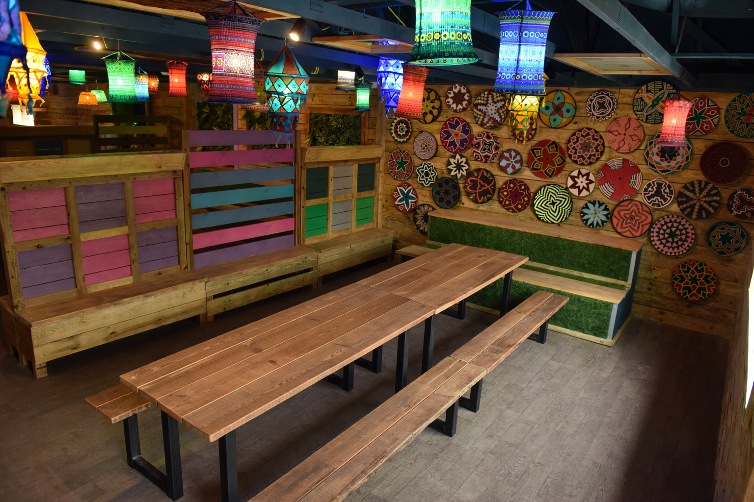 Indoor community meeting space at Hobbledown Epsom with colourful lantern lighting and table with benches.